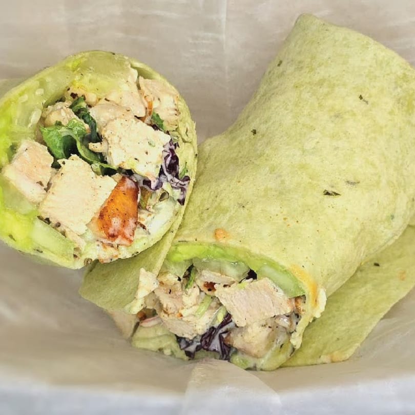 Two halves of a chicken and vegetable wrap from Main St. Deli, showcasing the fresh ingredients.
